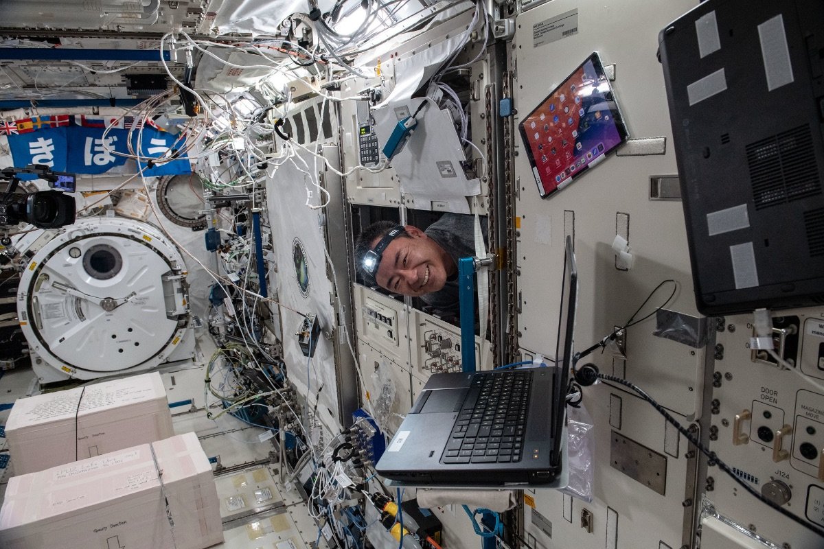 「きぼう」モジュール内のメンテナンス作業をしながら、ラックの後ろから頭を出す星出宇宙飛行士の様子 ©︎JAXA/NASA